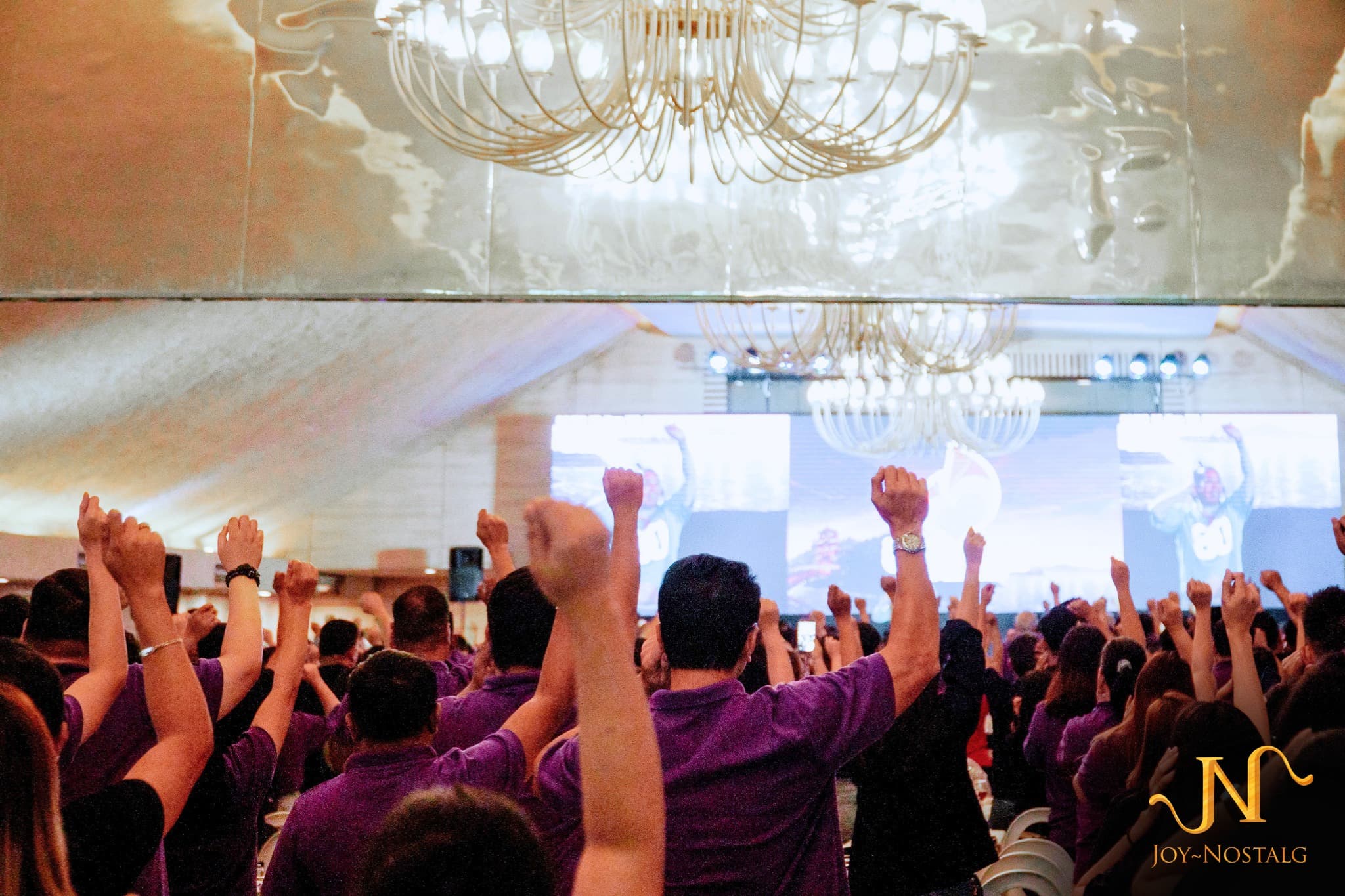 Joy~Nostalg employees raising their hands during a company gathering