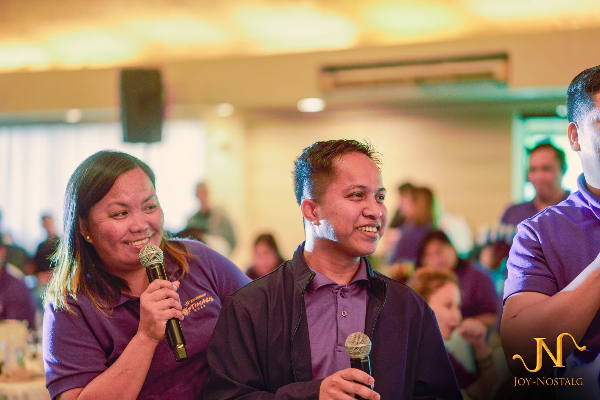 Two company-event hosts smiling while holding microphones